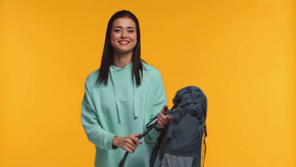 Viajante sorridente com mochila saindo isolado em amarelo
 - Filmagem, Vídeo
