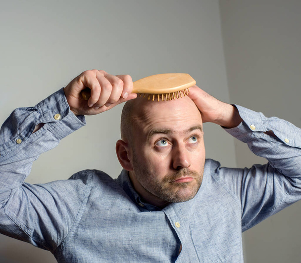 Caucasian confused bald man trying hair brush Problem with mens hair - Valokuva, kuva