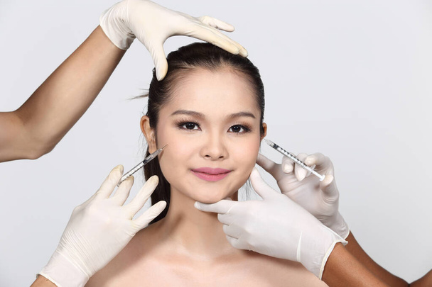 Molte mani che aiutano insieme con gli strumenti per Asian Beautiful Woman diagnosticano la struttura della pelle del viso e si preparano a truccare il sollevamento e il trattamento della pelle per uno sfondo liscio e bianco più luminoso isolato
 - Foto, immagini