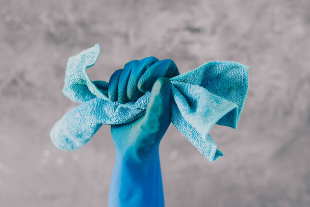 καθαρισμός και απολύμανση επιφανειών για την καταπολέμηση βακτηρίων και ιών, χέρι με μπλε γάντι καθαρισμού που συγκρατεί ύφασμα μικροϊνών  - Φωτογραφία, εικόνα