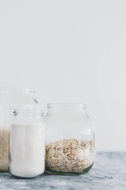 healthy non-perishable food ingredients for vegan pantry, glass jars with oats flour and rice  - Photo, image