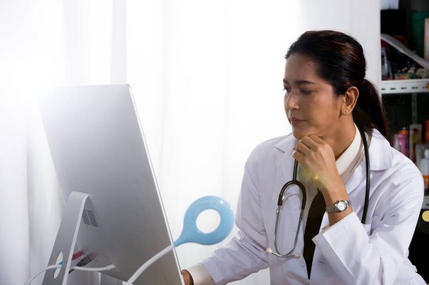 Женщина-врач в форме со стетоскопом, резиновые перчатки в больничной клинике, не проверяет на медстоле бумагу с монитором здоровья, место для копирования
 - Фото, изображение