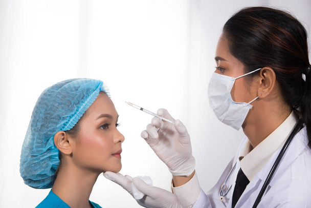 Ázsiai beteg kapott Botox, hialuronsav által India Közel-Kelet Orvos nő egyenruha sztetoszkóppal orvosi kórház klinika, koncepció orrplasztikai ellenőrzés előtt plasztikai műtét, másolás hely - Fotó, kép