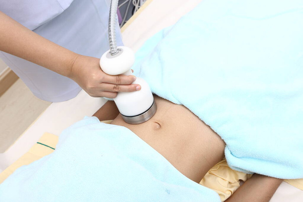 Tratamiento en la mujer asiática como paciente de grasa y examinar el problema con el instrumento de dispositivo de belleza médica de alta frecuencia en el estómago del vientre en la clínica hospitalaria
 - Foto, imagen