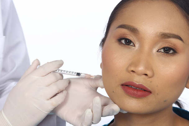 Kozmetikus Doctor Nurse injekciót kozmetikai kezelés kémiai arc, homlok, áll, állkapocs vonal a beteg arcát, ázsiai cserzett bőr nő meleg gondossággal, másolás helyet szöveges logó, stúdió világítás - Fotó, kép