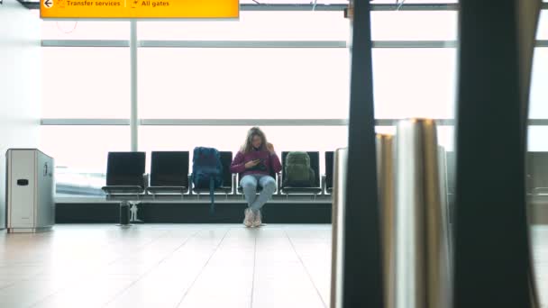 žena sleduje video na smartphonu v moderní letištní hale - Záběry, video