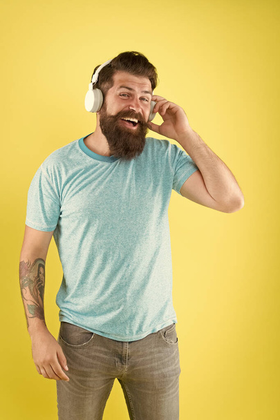 Freedom going wireless offers you is unparalleled. Wireless headphones designed to deliver clean sound. Bearded man listening music wireless gadget. Hipster happy using modern wireless headphones - Photo, Image