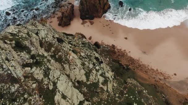 litoral com colinas rochosas perto da praia de areia com ondas azuis
 - Filmagem, Vídeo