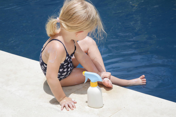 日焼け止め保護クリームを適用するかわいい幼児の女の子。夏休みの間、赤ちゃんを太陽から守るための日焼け止め化粧水。旅行中の子供の健康とスキンケア. - 写真・画像