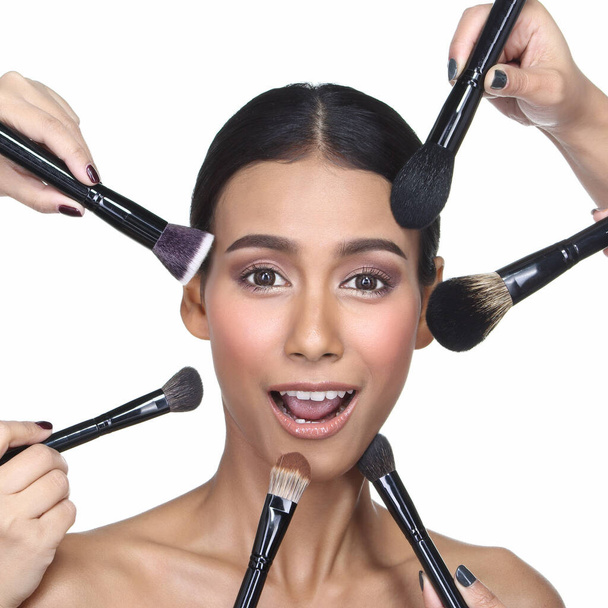 Many Hands helping Magic Tan Skin Woman wrapped black hair to be more beautiful with many size difference  brush, eye shadow lipsitck for many spot on big smile face,  studio lighting white background isolated - Photo, Image