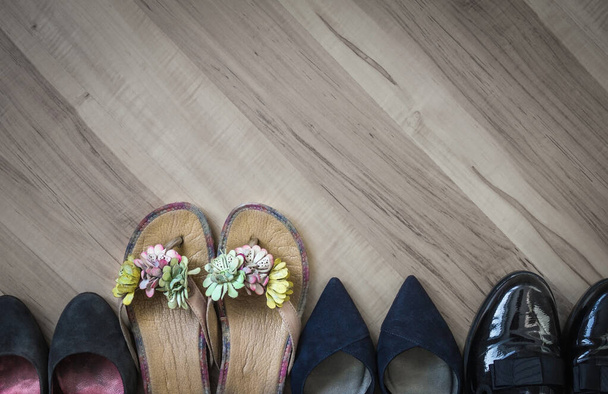 Zomer heldere vrouwelijke slippers opvallen in een rij van saaie kantoorschoenen. Spoedig het seizoen van de feestdagen, rust, vrij van de kledingvoorschriften. Bovenaanzicht, houten vloer. - Foto, afbeelding