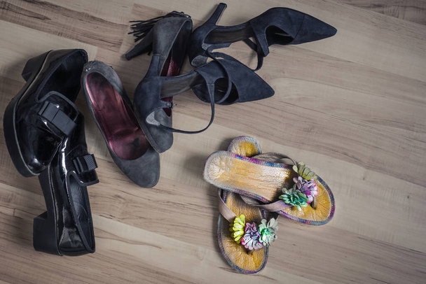 Tmavé, nudné pracovní boty stranou, před nimi lehkovážné sandály s květinami. Čekání na dovolenou, sezónu prázdnin, léto, odpočinek, dovolenou. Pohled shora. - Fotografie, Obrázek