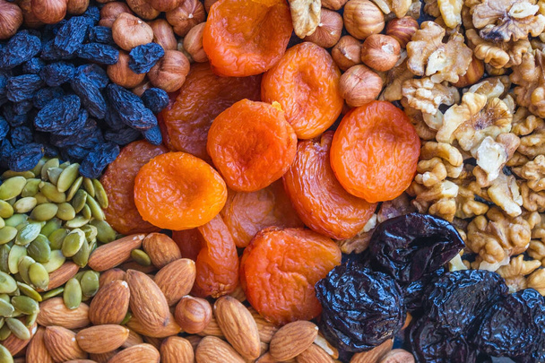 Nützliches Essen, richtige Ernährung. Fülle, Auswahl an Nüssen und Trockenfrüchten. Im Zentrum stehen orangefarbene Aprikosen. Natürliches, biologisches Produkt. - Foto, Bild