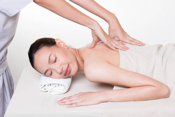 Μασάζ σώματος σε συγκεκριμένη γυμνή πλάτη της Ασιατικής γυναίκας πιέζοντας τα δάχτυλα στον πόνο ή το στρες σημείο των μυών για να χαλαρώσετε. Θεραπευτής Spa μασάζ σώματος γυναίκα χέρια θεραπεία για τον πελάτη, απομονώνονται σε λευκό - Φωτογραφία, εικόνα
