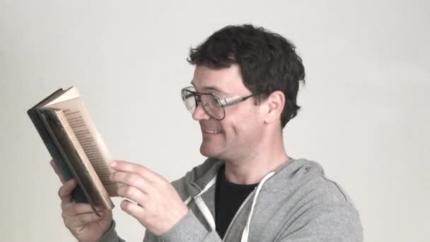 Model released man in studio wearing geeky glasses overly enjoys a classic book. - Video