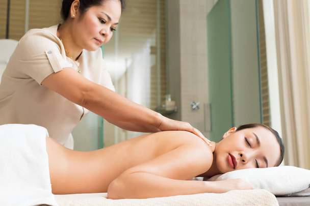 Body Massage on naked back of Mix Race Caucasian Asian woman by pressing fingers on pain or stress muscle point to release relax.  Therapist Spa body massage woman hands treatment on customer - Fotó, kép