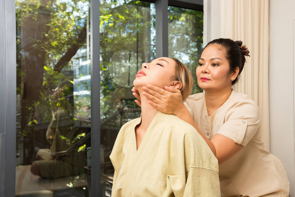 Masöz esneme masajı Beyaz ırk Asyalı kadınların omuzlarında boyun ve omurga gerilmesi ağrıyı ve stresi azaltmak için spa odasında yapılır. Geleneksel Tayland Masaj Konsepti. - Fotoğraf, Görsel