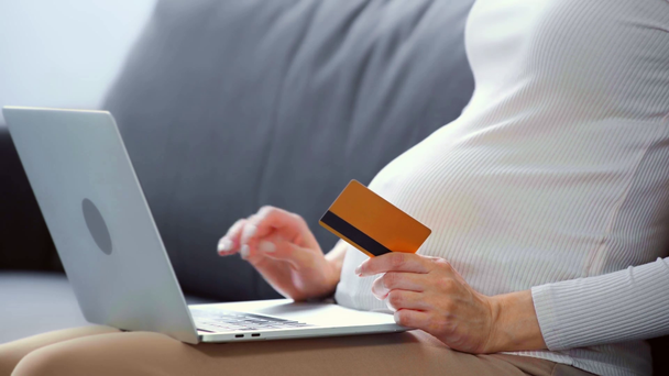Cropped view of pregnant woman with laptop and credit card on sofa  - Footage, Video