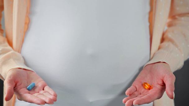 Vista cortada da mulher grávida segurando pílulas coloridas
 - Filmagem, Vídeo