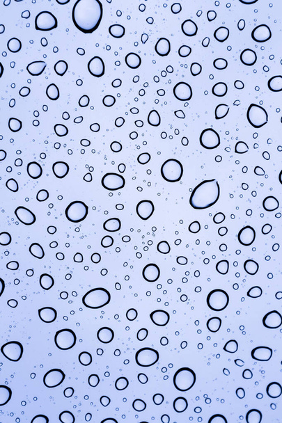 κλείσιμο των σταγόνων βροχής σε μια ηλιοροφή σε μια συννεφιασμένη ημέρα από το εσωτερικό του αυτοκινήτου προοπτική με μια μπλε απόχρωση - Φωτογραφία, εικόνα