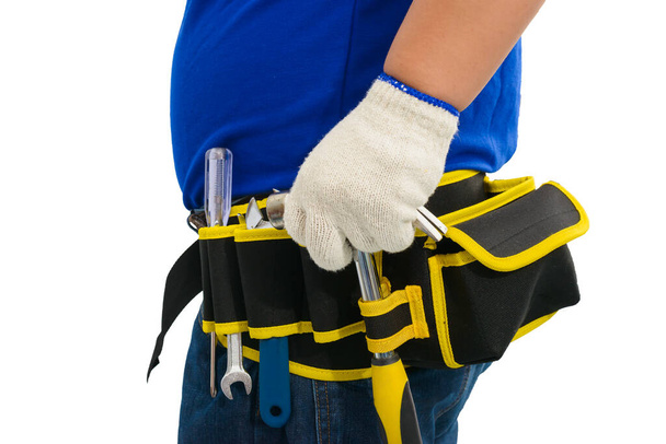 Крупный план строителя рабочих в синей рубашке с защитными перчатками, шлем с инструментальным поясом рука держит молоток изолирован на белом фоне с вырезкой дорожки
 - Фото, изображение