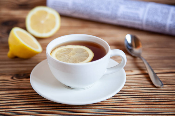 Cap of tea with lemon and paper on the wooden table. Teatime. - Valokuva, kuva