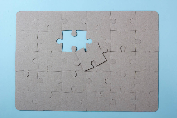 The last piece of cardboard puzzle on a blue background - Zdjęcie, obraz