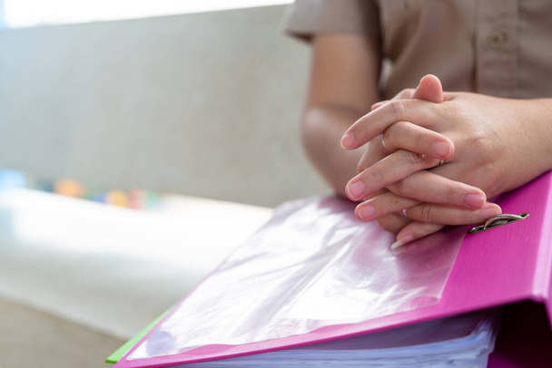 picture of closed up hands clasped on a pink file - Photo, Image