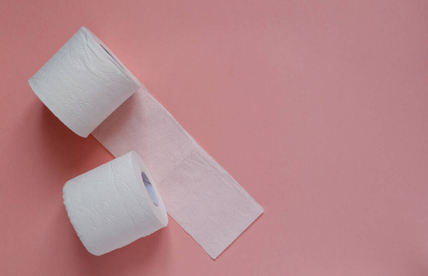Un montón de rollos de papel higiénico blanco sobre un fondo rosa. Pánico, concepto covid-19
. - Foto, imagen