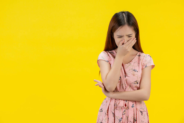 Sad woman. Female closed her hands on her face on a yellow background - Fotografie, Obrázek