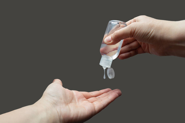 COVID-19 Fermer les mains de la femme à l'aide d'un distributeur de gel désinfectant pour les mains sur fond gris. Concept de soins de santé
. - Photo, image