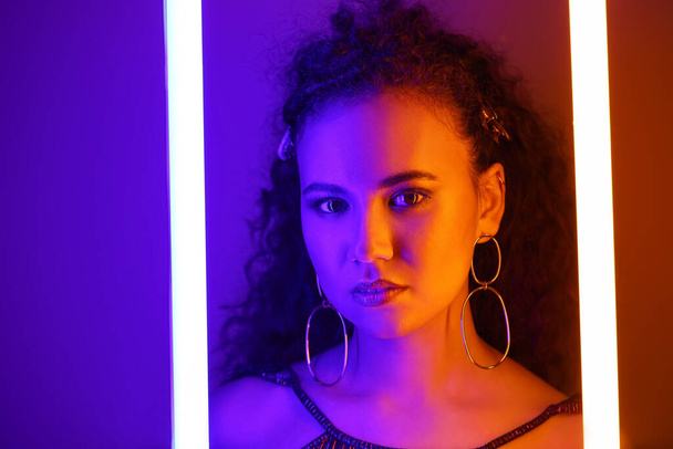 Beautiful African-American woman with neon lamps on color background - Foto, Imagem