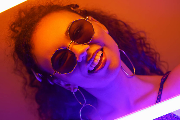 Beautiful African-American woman with neon lamps on color background - Zdjęcie, obraz