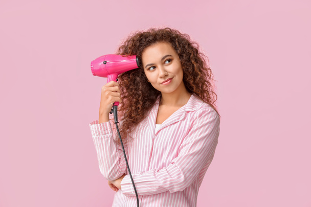 Beautiful young African-American woman with blow dryer on color background - Фото, зображення