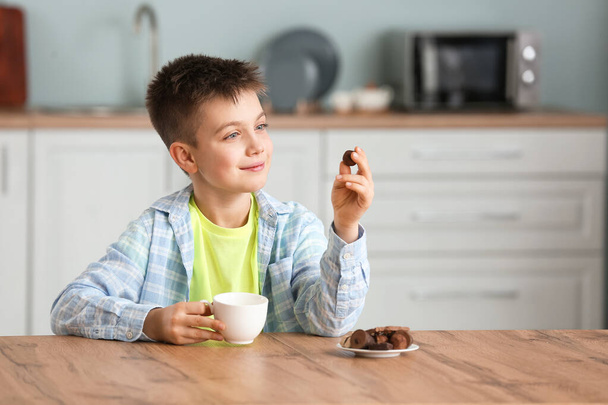Bonito menino comendo doces de chocolate na cozinha
 - Foto, Imagem