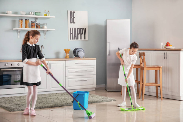 Cute little chambermaids cleaning kitchen - 写真・画像