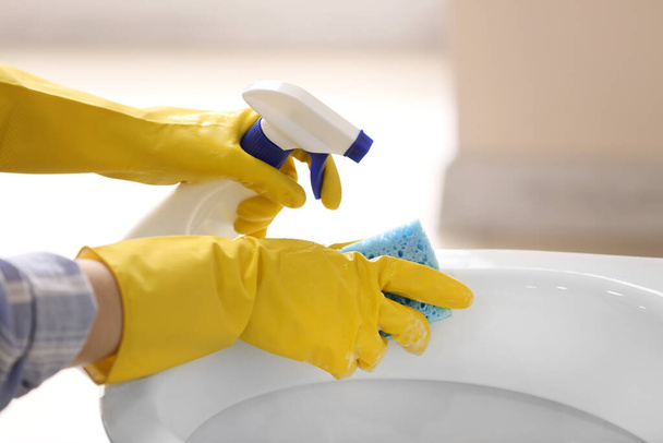 Woman cleaning toilet bowl in bathroom - Foto, Imagen