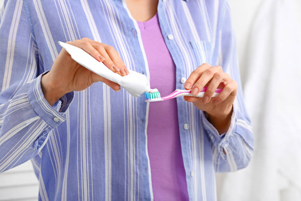 Vrouw met tandenborstel en plakken in de badkamer - Foto, afbeelding