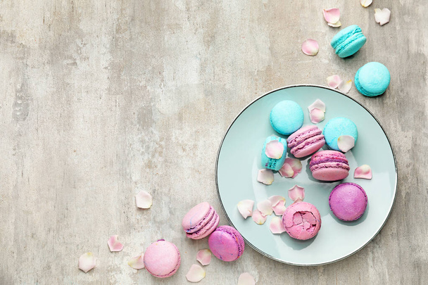 Tasty macarons with plate on grey background - Foto, afbeelding