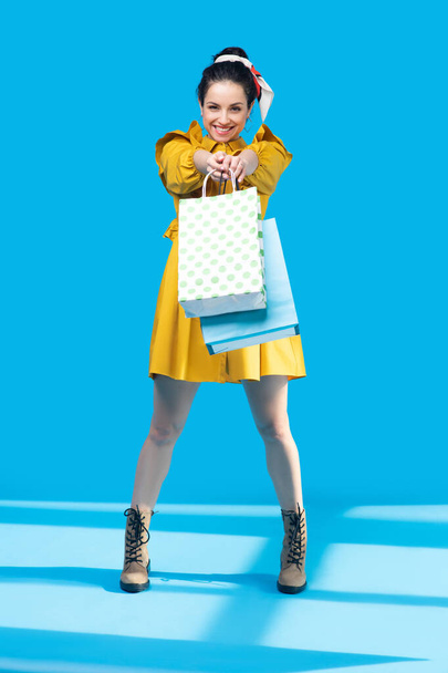 Young woman in a mustard dress standing with bags in her hands - Photo, Image