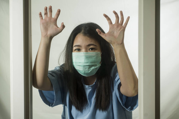 covid-19 pandemic - dramatic portrait of young scared and frightened Asian Korean woman in medical mask isolated on home lockdown and quarantine during contagious virus outbreak - Foto, immagini