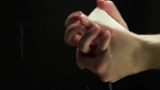 Young person washing his hands with soap at black background to eliminate germs and protect against dirt and bacteria. Personal hygiene cleansing and body well being. - Záběry, video