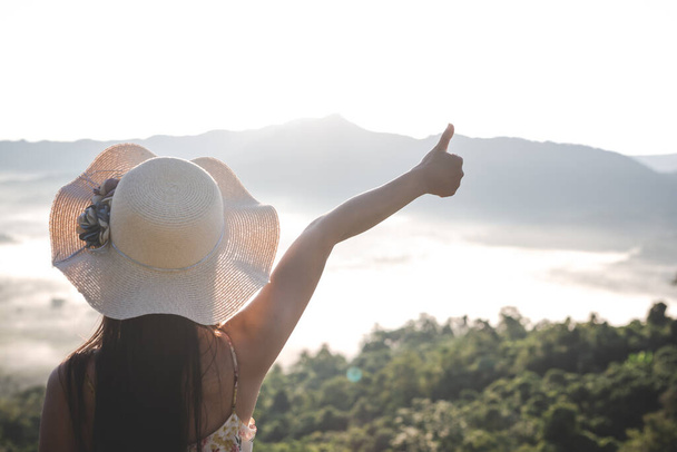 woman spreading arms with her thumbs up, standing high on the viewpoint - Foto, Bild