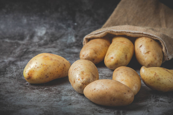 Aardappelen giet uit zakken op grijze vloer  - Foto, afbeelding