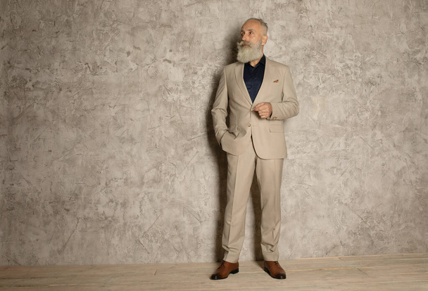 Portrait of mature businessman in suit standing on grey background. Copy space. - Foto, Bild
