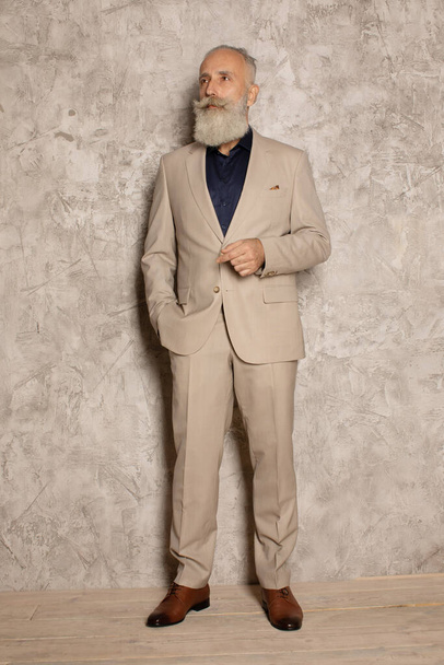 Portrait of mature businessman in suit standing on grey background. Copy space. - Fotografie, Obrázek