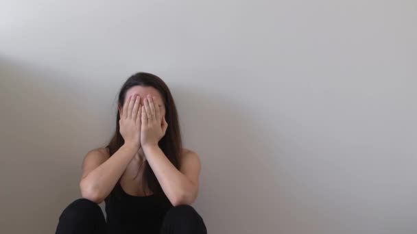 Egy depressziós fiatal nő. Magányos ember ül a padlón a fal mellett..  - Felvétel, videó