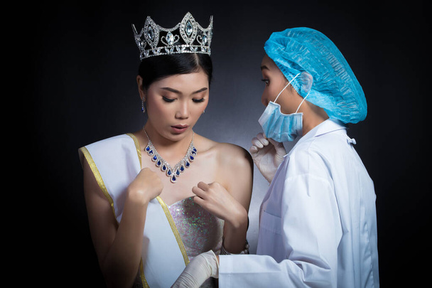 Miss Schönheitskönigin Wettbewerb mit Diamant Krone Schärpe wird von Kosmetikerin Doktor überprüft und empfehlen, sich vor Plastische Chirurgie, Hautbehandlung, vergrößern Brustimplantat - Foto, Bild