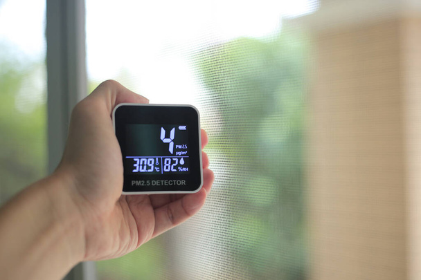 Medições da qualidade do ar. homem mão segurando portátil PM 2.5 sensor de partículas de poeira pequena. baixo teor de partículas no ar indicou bom ar respirável saudável. cidades habitáveis com bom ambiente
. - Foto, Imagem
