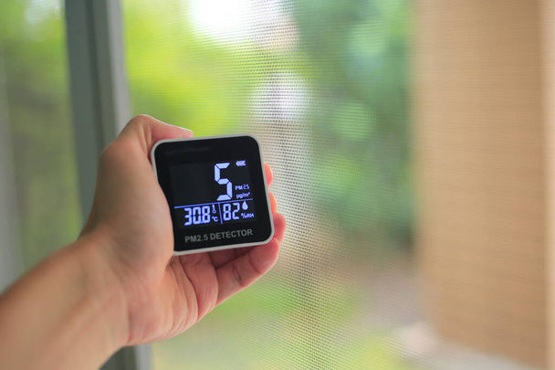 Měření kvality ovzduší. man hand holding handheld PM 2.5 small dust particles sensor. Nízké částice ve vzduchu indikovaly dobrý zdravý dýchatelný vzduch. obyvatelná města s dobrým prostředím. - Fotografie, Obrázek